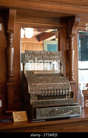 Une vue verticale d'une caisse ancienne en laiton ornée sur un comptoir arrière en bois sculpté avec des colonnes tournées et un miroir à New York. Banque D'Images
