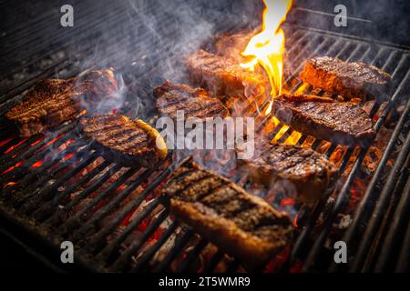 Steaks de bœuf sur le gril avec des flammes. Concept de nourriture et de cuisine. Banque D'Images