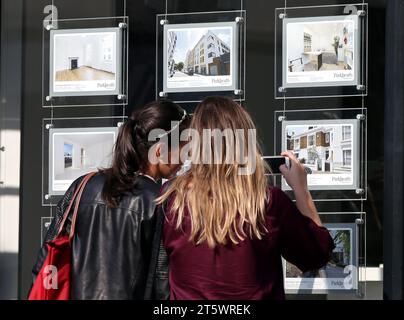 Photo du dossier datée du 08/06/2016 d'un couple de femmes étudiant les panneaux de prix d'une maison dans une fenêtre d'agent immobilier, à Kentish Town, Londres. Le prix moyen de l’immobilier au Royaume-Uni a bondi d’environ 3 000 £ par mois en octobre – ce qui marque la première augmentation mensuelle depuis mars – selon Halifax. La banque a déclaré que les prix des logements ont augmenté de 1,1% en moyenne en octobre, contre une baisse de 0,3% en septembre. Une faible offre de maisons à vendre aura probablement des prix plus élevés à court terme, a déclaré Halifax. Date de publication : mardi 7 novembre 2023. Banque D'Images