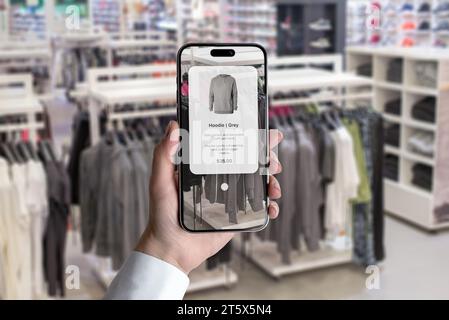 Avenir du concept d'achat dans le magasin de vêtements avec une application intelligente. Explorez les caractéristiques des vêtements en pointant simplement le téléphone Banque D'Images