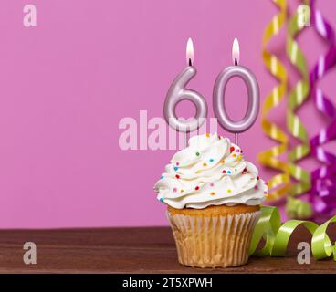 Gâteau d'anniversaire avec bougie numéro 60 - sur fond rose. Banque D'Images