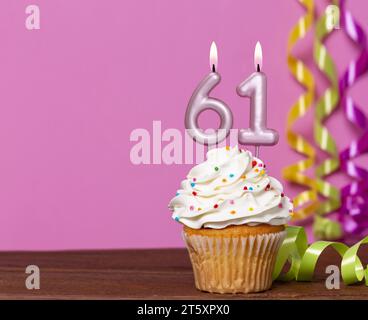 Gâteau d'anniversaire avec bougie numéro 61 - sur fond rose. Banque D'Images