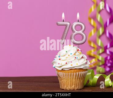 Gâteau d'anniversaire avec bougie numéro 78 - sur fond rose. Banque D'Images