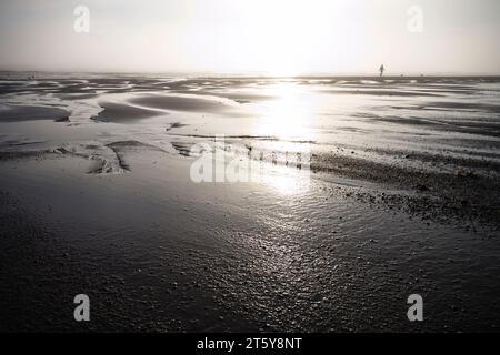 Homme promenant deux chiens au loin tôt le matin à Skegness Banque D'Images