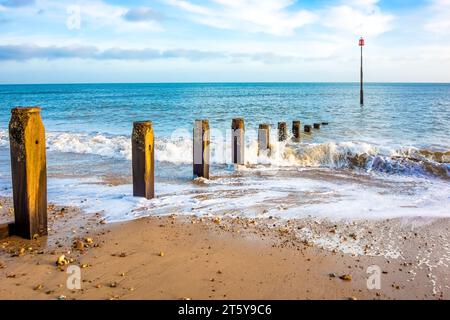 Vue sur la mer avec des vagues éclaboussant sur des groynes en bois classiques, plage de Hythe, Kent, Royaume-Uni Banque D'Images