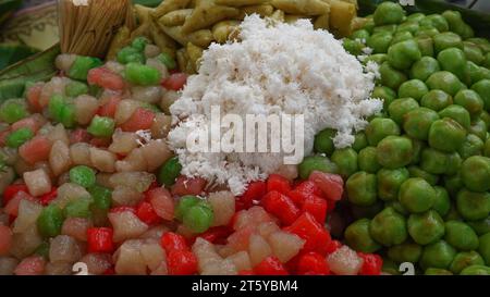 Collations traditionnelles du marché javanais indonésien, cénil de différentes couleurs et klepon vert à base de farine saupoudrée de noix de coco râpée Banque D'Images