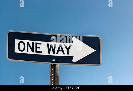 détail d'un panneau de signalisation à sens unique contre un ciel bleu Banque D'Images