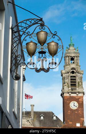 Derniers signes de l'ancien hôtel à Colchester ; un panneau suspendu fixé sur l'ancien Cups Pub dans Trinity Street. Hôtel de ville de Colchester en arrière-plan. (136) Banque D'Images