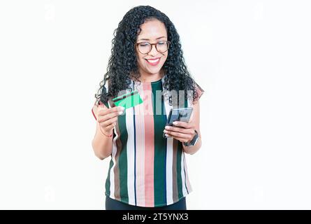 Fille afro souriante tenant des achats de carte de crédit en ligne avec le téléphone isolé. Heureuse jeune femme faisant des achats en ligne avec des téléphones portables et des cartes de crédit Banque D'Images