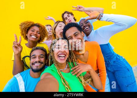 Heureux multiracial prenant un selfie souriant ensemble dans un fond jaune Banque D'Images