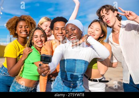 Femme musulmane prenant un selfie avec des amis multi-ethniques à l'extérieur Banque D'Images