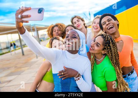 Heureuse femme africaine musulmane prenant un selfie en riant avec des amis Banque D'Images