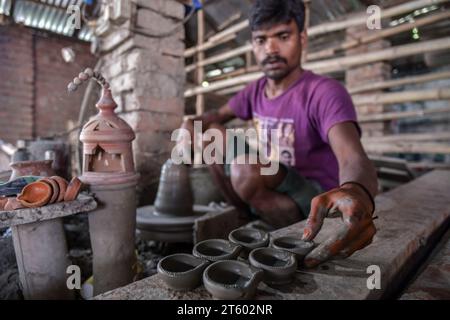 Un ouvrier fabrique une lampe en terre dans le village de poterie nommé Chaltaberia, à environ 40 km de la périphérie de Kolkata au Bengale occidental. Tout le village est en plein rythme de la production de lampes en terre et d'idoles avant le festival Diwali en Inde. Lampes en terre vendues dans toutes les villes indiennes comme Kolkata, Delhi, Mumbai, Hyderabad, Gujarat, Assam, Patna et Rajasthan, surtout pendant la saison des festivals. Même les lampes en terre sont exportées vers l'extérieur de l'Inde avant les célébrations de Diwali. Banque D'Images