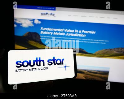 Personne tenant un téléphone cellulaire avec le logo de la société canadienne South Star Battery Metals Corp. devant la page Web de l'entreprise. Concentrez-vous sur l'affichage du téléphone. Banque D'Images