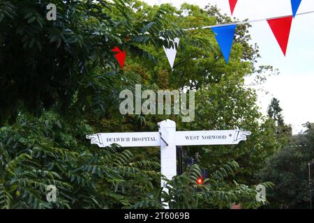 Jolis panneaux blancs dans le village de Dulwich, avec des bannières colorées au-dessus de la tête entourées de verdure Banque D'Images