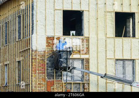 Technicien pulvérisant la couche de mousse d'isolation thermique sur le mur extérieur d'une maison d'habitation en utilisant le pistolet à plusieurs composants pour la mousse de polyuréthane Banque D'Images