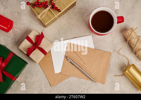 Chocolat chaud traditionnel près des enveloppes et des coffrets cadeaux avec des bougies sur texture grise, Noël Banque D'Images