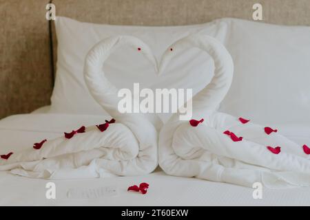 Chambre douce en vacances, décoration de serviette de cygne sur le lit avec oreiller blanc dans l'intérieur de la chambre. Banque D'Images