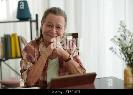 Portrait de femme âgée souriante assise au bureau avec tablette Banque D'Images