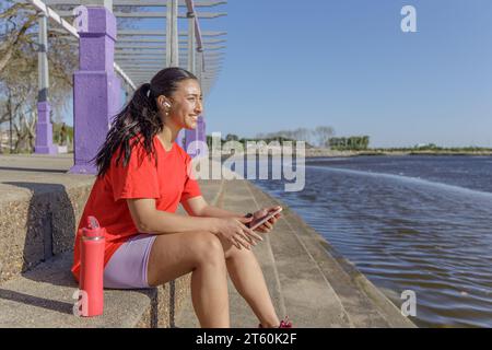 Fille en sportswear assise sur les escaliers prenant une pause. Banque D'Images