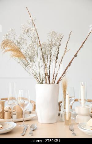 Réglage de table élégant avec des bougies, des fleurs séchées dans des vases et des verres Banque D'Images
