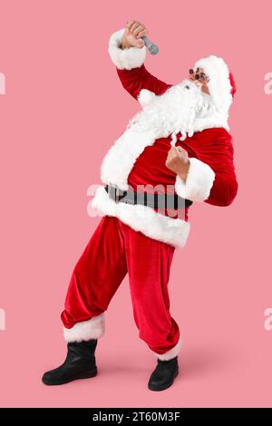 Cool Santa Claus avec microphone chantant sur fond rose Banque D'Images