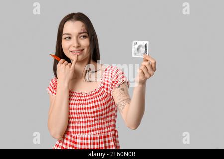 Belle jeune femme avec des préservatifs sur fond gris. Concept de sensibilisation À L'AIDE Banque D'Images