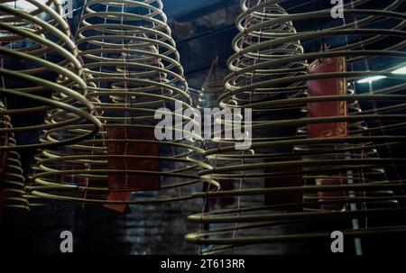 Plusieurs grandes bobines d'encens jaunes suspendues en piles du plafond dans un sanctuaire chinois. Grandes bobines d'Encens en spirale en forme de cloche, mise au point et flou. Banque D'Images