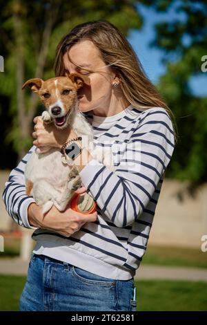 Femme tient son chien sur les mains et embrassant avec elle. Heureuse propriétaire femme embrassant et embrassant un ami mignon. Soins aux animaux Banque D'Images