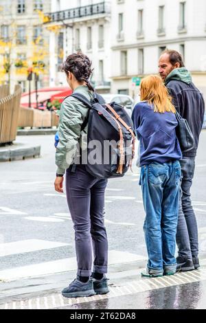 Trois personnes attendant au croisement de rue dans le centre-ville - Paris 20, France. Banque D'Images