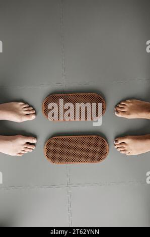 Vue de dessus gros plan de deux paires de pieds debout par planche à ongles sadhu dans le studio de yoga, espace de copie Banque D'Images