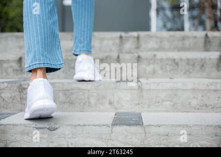 Avec détermination, une femme en baskets prend les escaliers de la ville, reflétant ses progrès incessants Banque D'Images