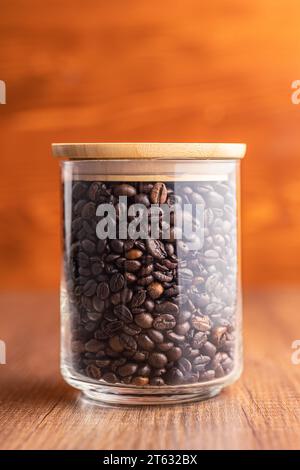 Grains de café torréfiés en pot sur la table en bois. Banque D'Images