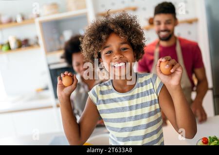 Heureuse famille afro-américaine préparant des aliments sains dans la cuisine, s'amuser ensemble le week-end Banque D'Images