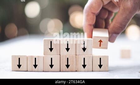 Main plaçant le cube de bloc en bois inverser la direction de perspective flèche vers le haut de façon opposée penser leadership sur fond de table blanc. Signe changeant d'esprit Banque D'Images