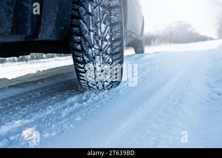 La voiture est sur une route d'hiver enneigée. Gros plan des pneus d'hiver. Banque D'Images