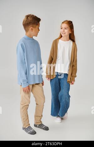 joyeuse petite fille dans le cardigan tricoté souriant au garçon preteen sweat-shirt bleu, concept de mode Banque D'Images