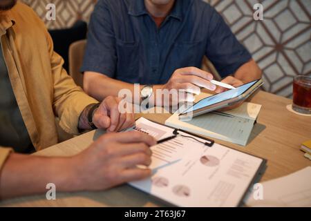 Image rognée de gens d'affaires discutant de rapports avec des données financières en réunion Banque D'Images