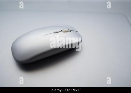 Une photo minimaliste d'une souris d'ordinateur blanche placée sur une surface grise lisse floue Banque D'Images