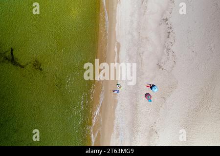 Du dessus drone capturé vue de dessus d'une plage de sable en Sardaigne, en Italie, avec des gens méconnaissables se relaxant sous des parasols colorés et des serviettes. Banque D'Images