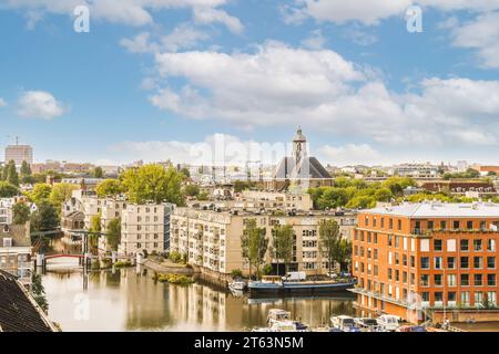 Vue aérienne du paysage urbain avec des bâtiments résidentiels contemporains et des bateaux amarrés sur la rivière sous un ciel nuageux Banque D'Images