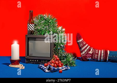 Téléviseur vintage entouré d'une gamme d'objets, y compris une bouteille avec une étiquette rayée, des raisins frais sur un tissu à carreaux, une bougie blanche A. Banque D'Images