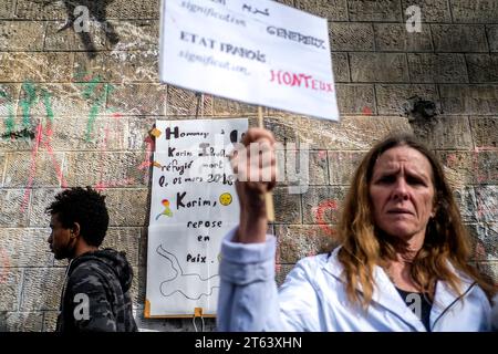 Michael Bunel/le Pictorium - exil au pays des droits de l'homme - 12/03/2018 - France/Ile-de-France (région)/Paris - une femme de WA tient une pancarte sur laquelle est inscrit le nom Karim, tandis qu'une pancarte en hommage au défunt jeune migrant soudanais est affichée sur le mur. Karim Ibrahim, un jeune migrant soudanais, est décédé jeudi 8 mars près du premier centre d’accueil et d’hébergement pour migrants mis en place en novembre 2016 par la ville de Paris et géré par Emmaus. 11 mars 2018. Paris. France. En octobre 2015, la municipalité a présenté dix-huit engagements dans un document intitulé « Mobil Banque D'Images