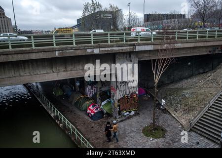 Michael Bunel/le Pictorium - exil au pays des droits de l'homme - 08/12/2021 - France/Ile-de-France (région)/Paris - les réfugiés ont installé un campement d'une trentaine de tentes sous un pont sur la rocade nord-est de Paris. Le camp est situé sur une rive le long du Canal de l'Ourcq, rue Delphine Seyrig à Pantin. Au premier plan, l'une des tentes porte le drapeau britannique imprimé sur la toile. 07 décembre 2021. Pantin, France. En octobre 2015, la municipalité a présenté dix-huit engagements dans un document intitulé « mobiliser la communauté parisienne pour accueillir les réfugiés ». Le document ope Banque D'Images