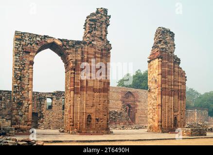 Qutb Minar le matin brumeux vu de l'intérieur des jardins historiques et des ruines flanquées d'arbres à Delhi, Inida. Banque D'Images