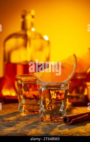 Verres de liqueur d'orange garnis de sucre et de cannelle en poudre. Liqueur d'orange avec des fruits frais sur une vieille table en bois. Banque D'Images