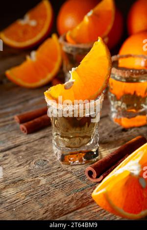 Verres de liqueur d'orange garnis de sucre et de cannelle en poudre. Liqueur d'orange avec des fruits frais sur une vieille table en bois. Banque D'Images