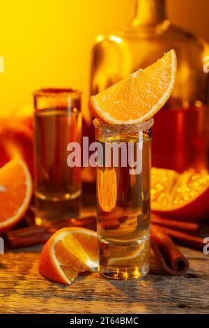 Verres de liqueur d'orange garnis de sucre et de cannelle en poudre. Liqueur d'orange avec des fruits frais sur une vieille table en bois. Banque D'Images