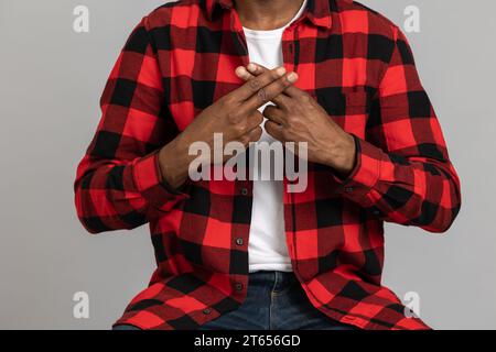 Homme barbu noir méconnaissable portant une chemise à carreaux rouge montrant des gestes sourds-muets Banque D'Images