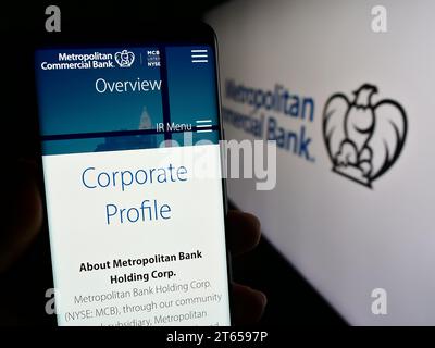 Personne détenant un téléphone portable avec la page Web de la société financière américaine Metropolitan commercial Bank (MCB) avec logo. Concentrez-vous sur le centre de l'écran du téléphone. Banque D'Images